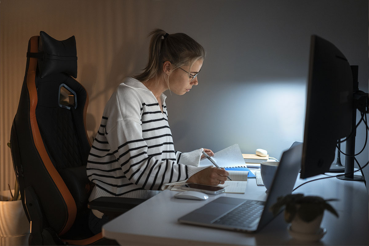 Estudiante estudiando por la noche con apuntes y ordenador